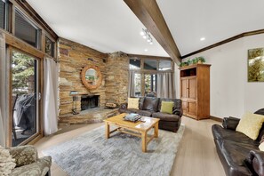 Una sala de estar con chimenea de piedra, sofá de cuero y una mesa de centro de madera.