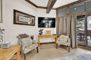 A living room with a wooden desk, two patterned armchairs, a television, and a large window with curtains. - NEWLY Remodeled, Ski and stay at the BEST ! PRIVATE HOT TUB!, 100yds to ski! (Park City)