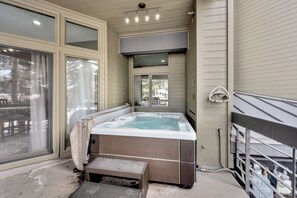 Un jacuzzi con terraza de madera y un espacio cubierto con un banco.