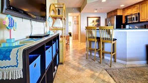 A kitchen with wooden cabinets, a microwave, and a dining area with two chairs.