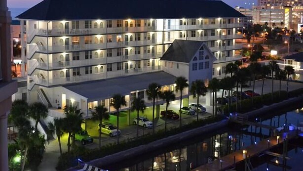 A multi-story hotel with balconies, a swimming pool, and a parking area.