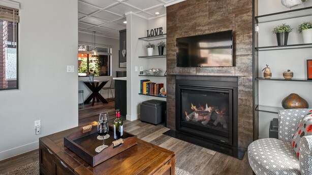 Een moderne woonkamer met een open haard, een bijzettafeltje met drankjes en een boekenkast met decoratieve objecten.
