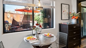 Een eetgedeelte met een ronde tafel, stoelen, een wijnglas en een fles wijn.