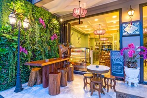 An indoor cafe with a green wall, wooden stools, and a bar area. - U Residence Hotel (Krabi)