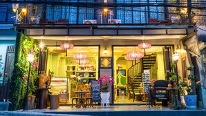 A multi-story building with balconies, a shop on the ground floor, and decorative lighting. - U Residence Hotel (Krabi)