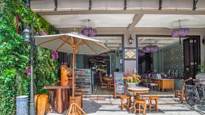 An outdoor cafe with wooden furniture, a green wall with plants, and a signboard. - U Residence Hotel (Krabi)
