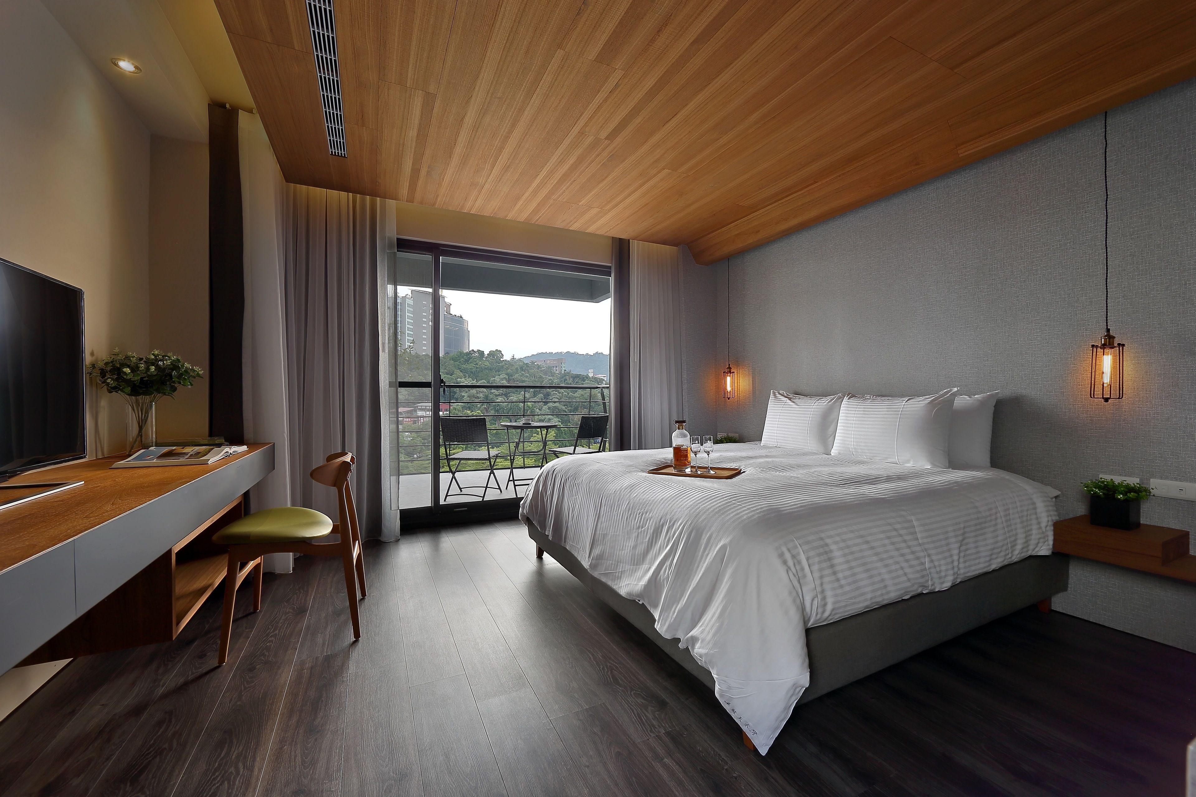 Quarto moderno com cama grande, uma mesa de escritório e varanda com vista.