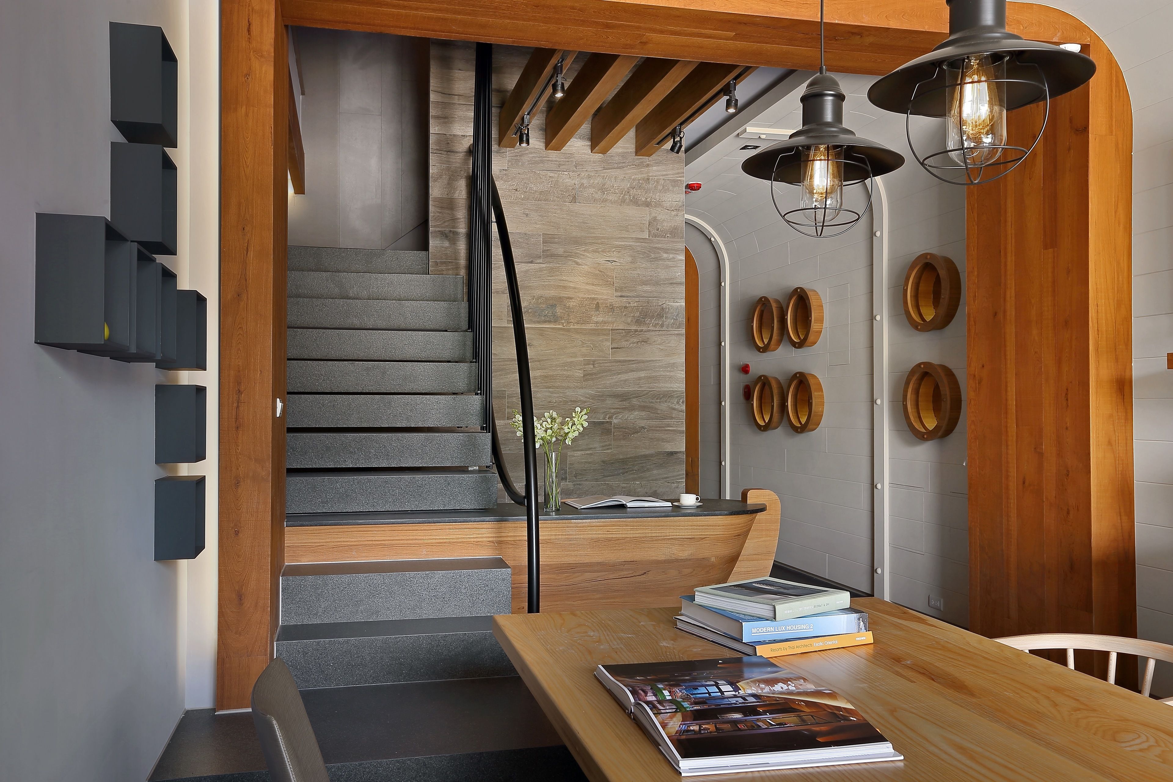 A modern interior with a wooden reception desk, a staircase with grey steps, and a wall with circular wooden decorations.