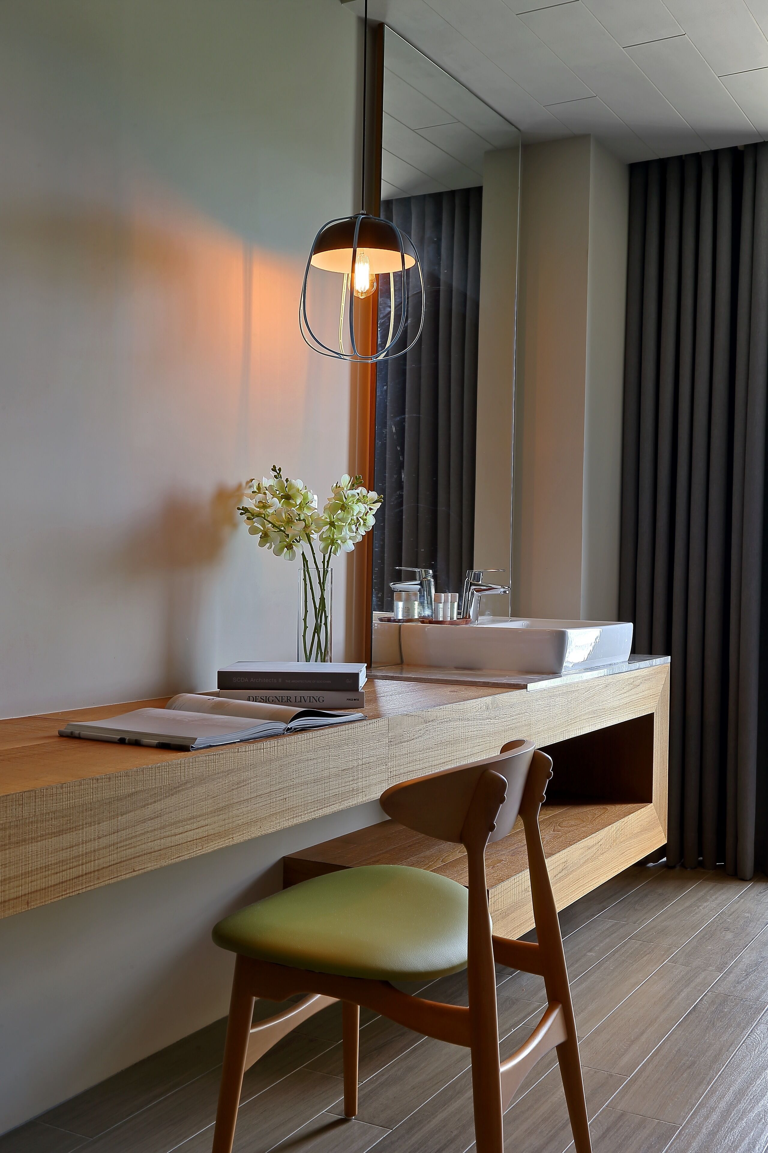 Een moderne badkamer met een houten wastafelmeubel, een grote spiegel en een vaas met bloemen.