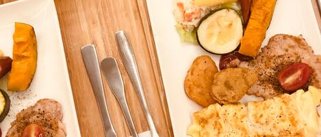 Bandeja de desayuno con platos de comida, cubiertos y un vaso de zumo de naranja.