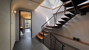 A modern staircase with a wooden finish and metal railings, leading to an upper floor. - Blue Sky Bay B&B (Yuchi)