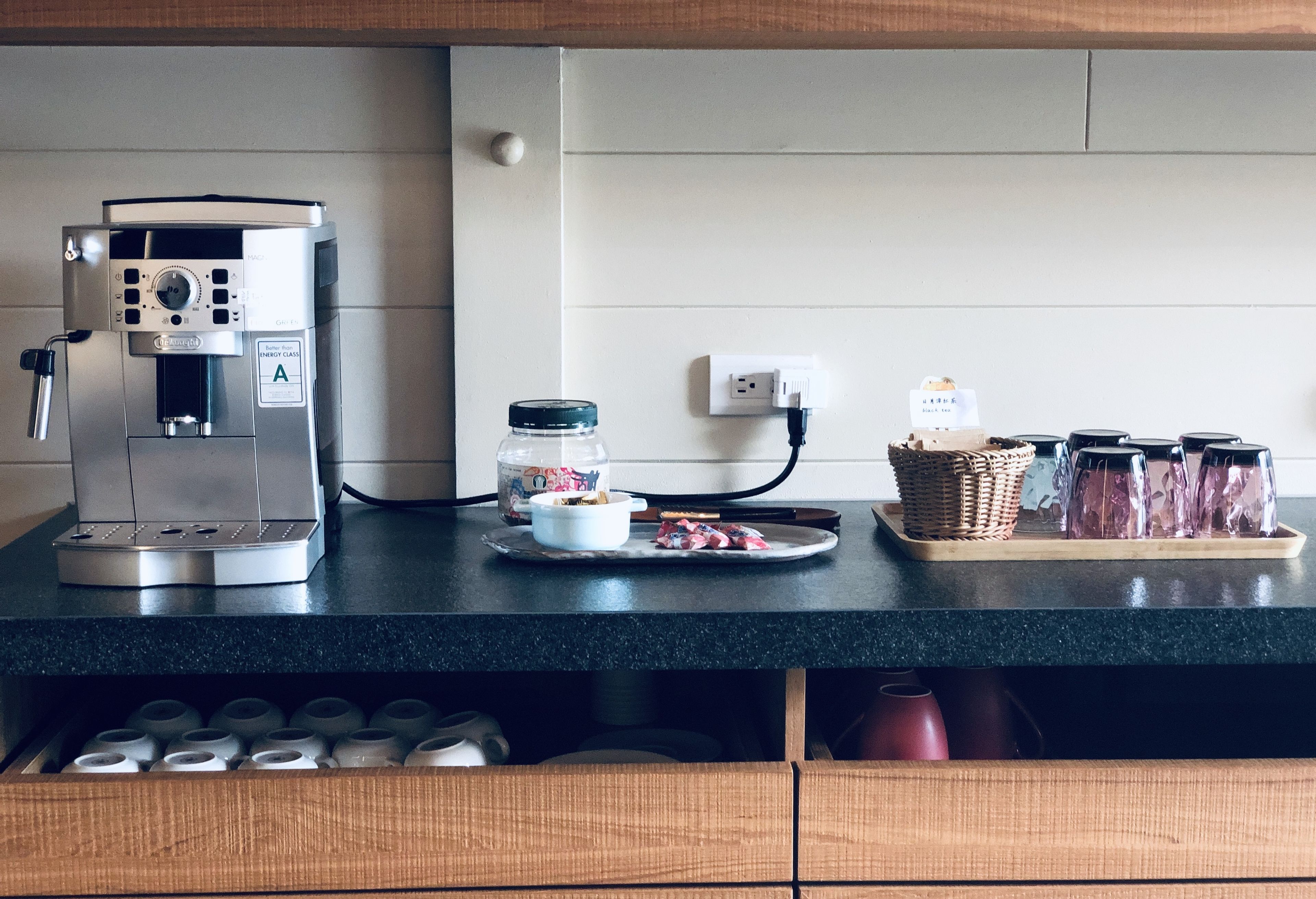 A kitchen counter with a coffee machine, a bowl of food, and jars of condiments.