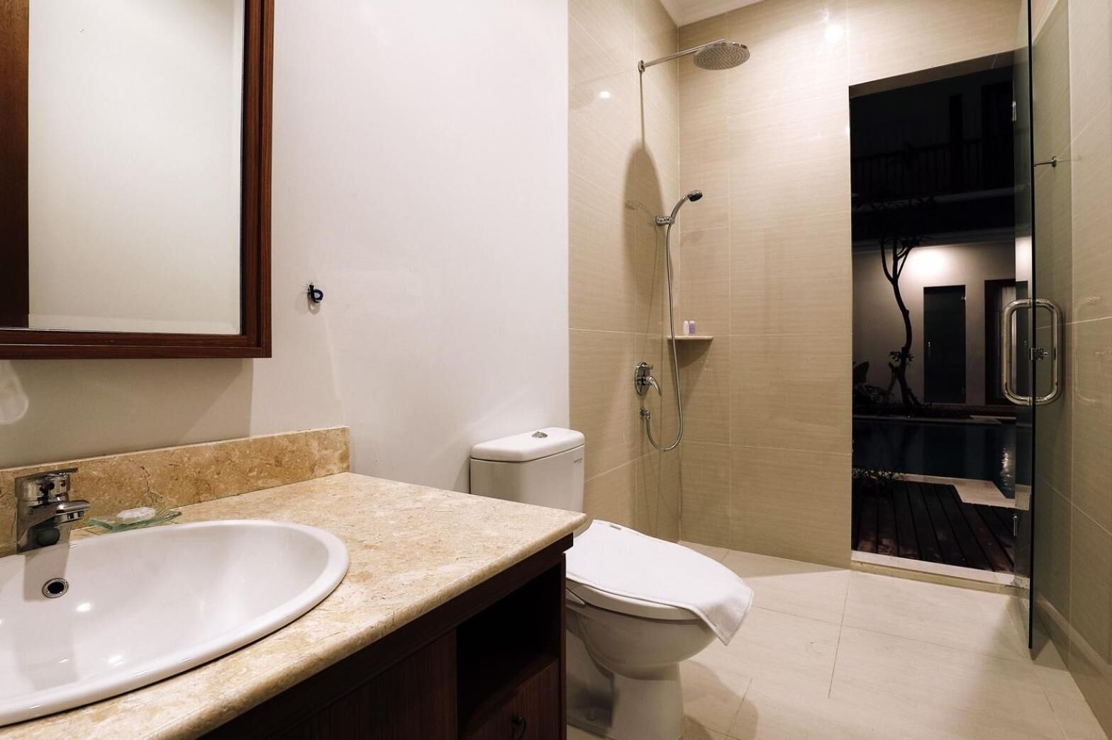 A modern bathroom with a large sink, toilet, and walk-in shower.