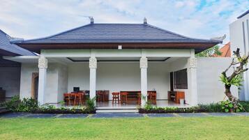 A modern house with a covered porch, a dining area with wooden furniture, and a well-maintained lawn.