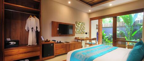 A bedroom with a large bed, wooden wardrobe, and a TV on the wall.