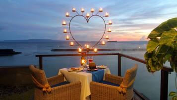 A romantic outdoor dining setup with wicker chairs, a table with a white tablecloth, and a heart-shaped light decoration.