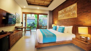 A bedroom with a large bed, wooden headboard, a TV, and a desk with a chair. - Sagara Candidasa by AHM (Karangasem)
