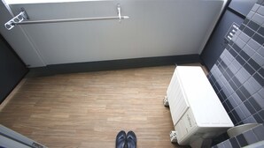A small, compact bathroom with a wooden floor, a radiator, and a towel rack. - 2500 Comics Room (Tokyo)