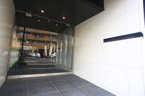Una entrada de edificio moderno con puerta de vidrio, un letrero que dice 