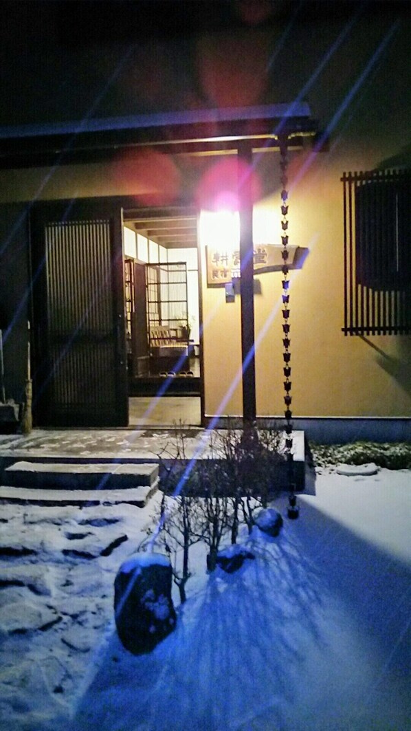 A building with a snow-covered entrance and a lit signboard. - guesthouse KOUNDO (Nikko)