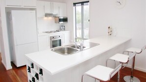 A modern kitchen with white cabinetry, a stainless steel sink, and a built-in wine cooler.