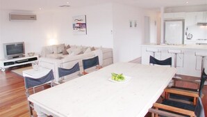 A modern living room with a sofa, a TV, and a dining area with a table and chairs.