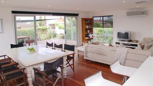 A spacious living area with a dining table, chairs, a sofa, and a television.