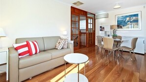 A modern living room with a sofa, a round coffee table, and a dining area with chairs and a table. - Moana Magic (Moana)