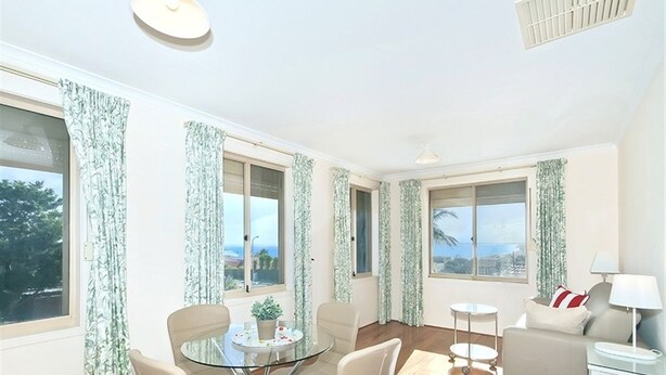 A modern living room with a glass dining table, a sofa, and a small side table. - Moana Magic (Moana)