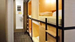 A hotel room with bunk beds, a small bathroom with a sink and mirror, and a shelf with toiletries. - Tokyo Tower View Guest House (Tokyo)