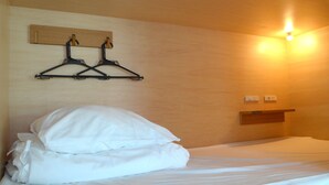 A neatly made bed with white linens, a wooden headboard, and a wall-mounted coat rack with black hangers. - Tokyo Tower View Guest House (Tokyo)