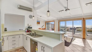 A modern kitchen with a large island, built-in appliances, and a view to the outside. - Queensland South (Aldinga Beach)