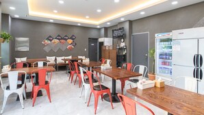 A modern dining area with wooden tables and red and white chairs, a refrigerator, and a menu board on the wall. - Incheon Pentastar Hotel (Incheon)
