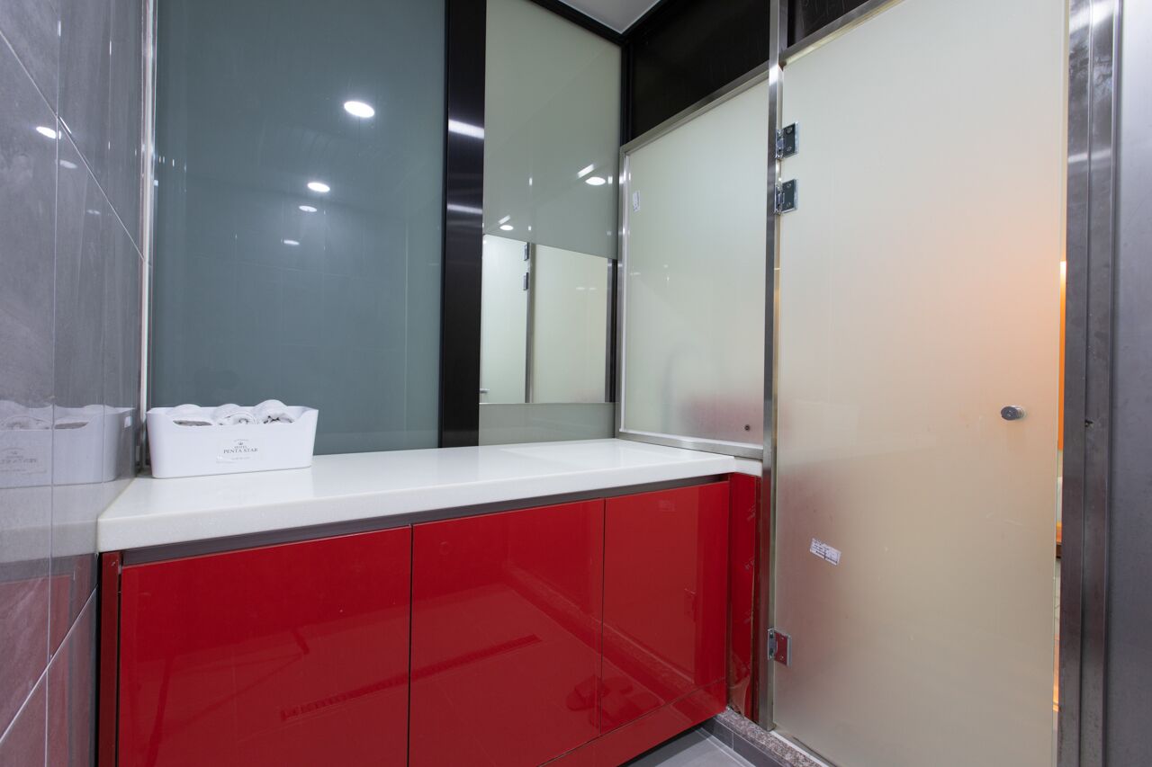 Une salle de bain moderne avec un comptoir blanc, un meuble rouge et un grand miroir.