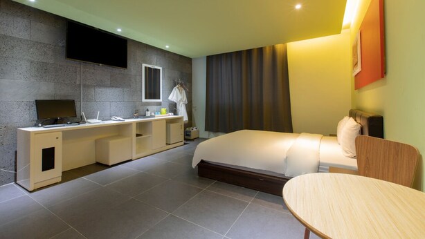 A modern hotel room with a bed, a desk with a flat-screen TV, a small table, and a sofa. - Incheon Pentastar Hotel (Incheon)