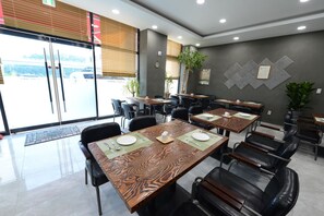 A restaurant interior with tables, chairs, and a view of the street outside. - Incheon Pentastar Hotel (Incheon)