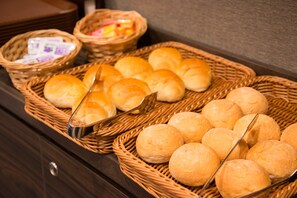 A buffet table with baskets of bread rolls and a metal serving spoon. - Sakura Sky Hotel (Tokyo)
