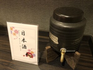 Uma garrafa de saquê sobre um suporte de madeira, ao lado de uma placa com caracteres japoneses.