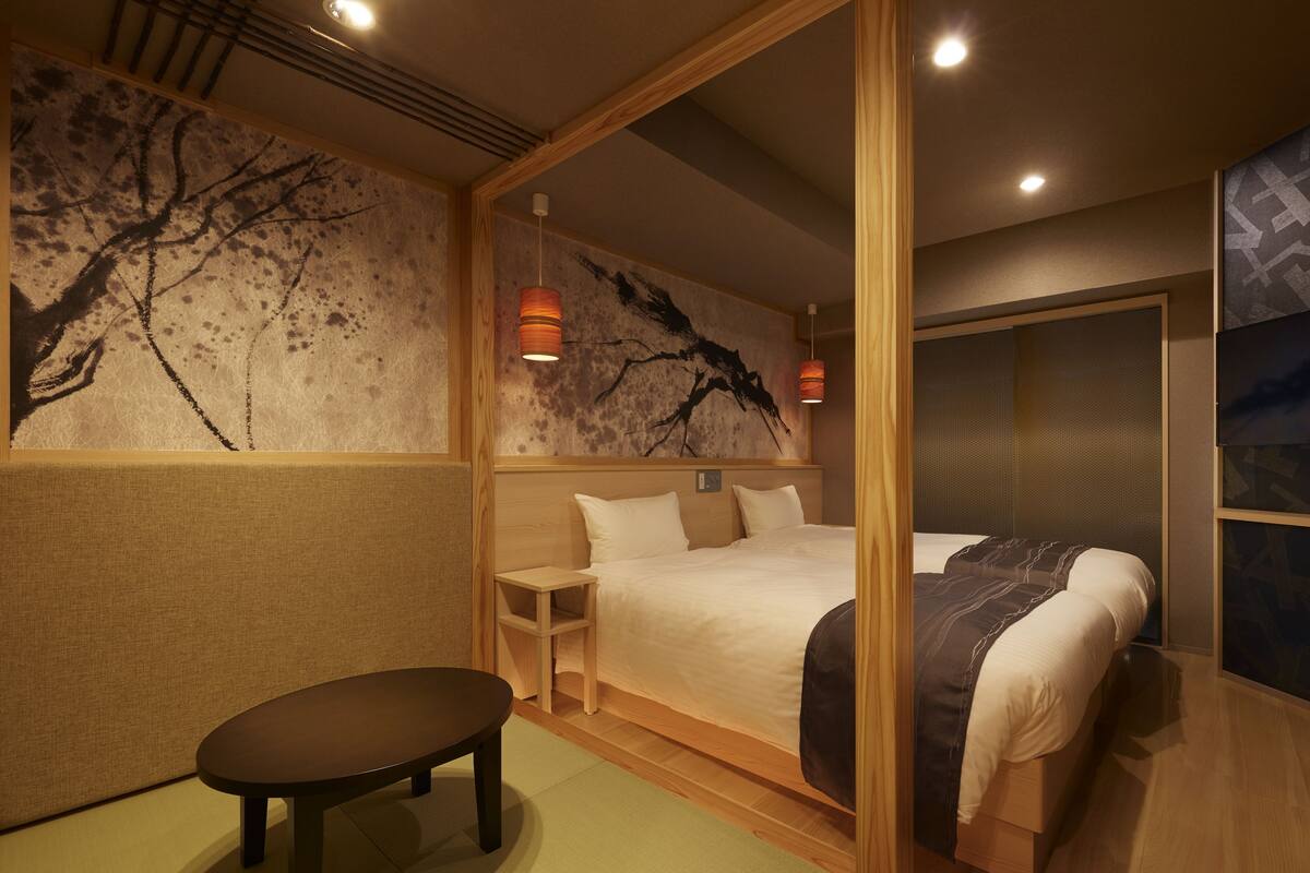 A hotel room with a bed, a small table, and a seating area.