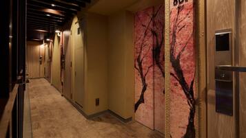 Un pasillo de hotel con paneles de madera, piso de baldosas y un diseño de rama de árbol en la pared.