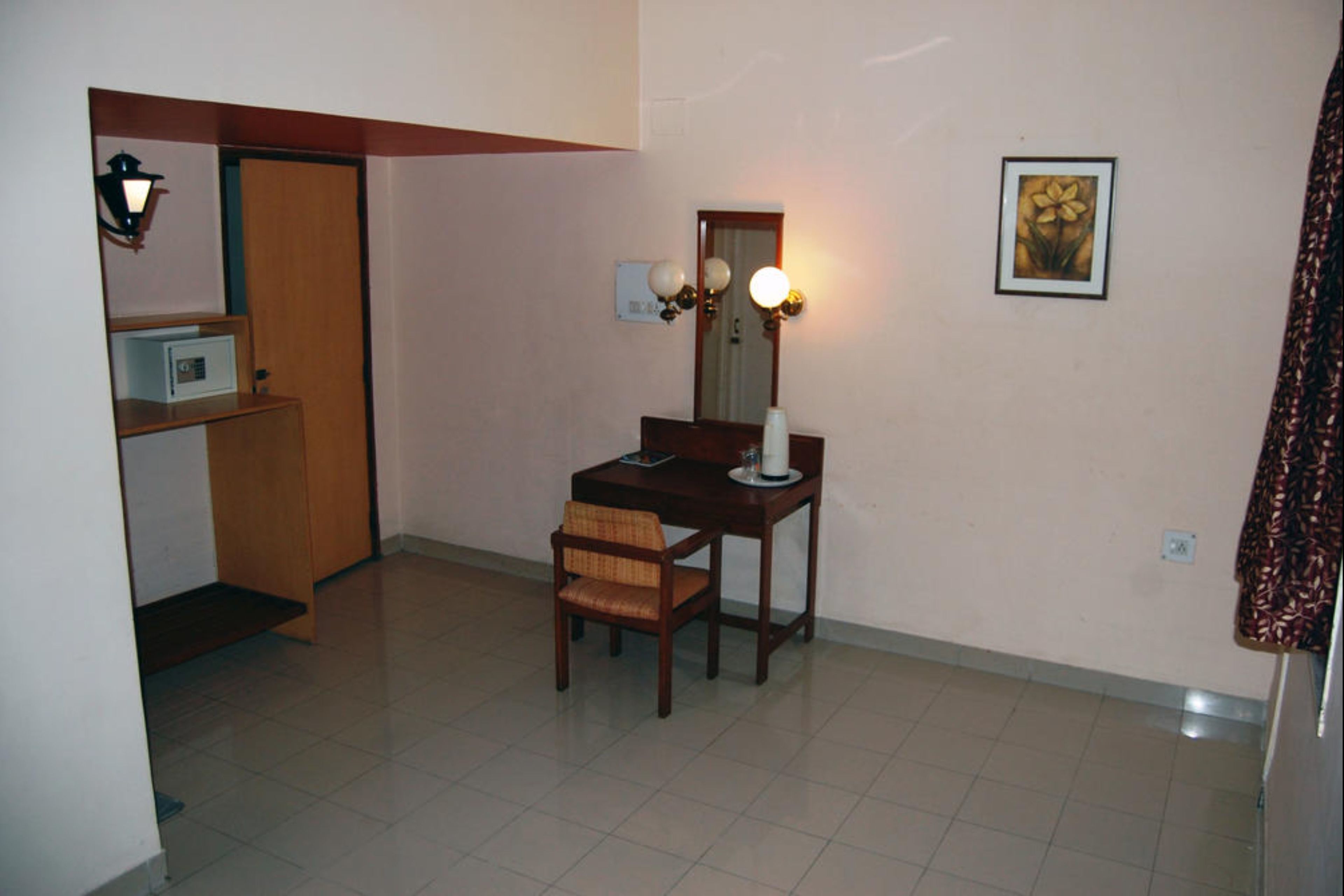 A small room with a wooden table, a chair, a mirror, and a wall-mounted light fixture.