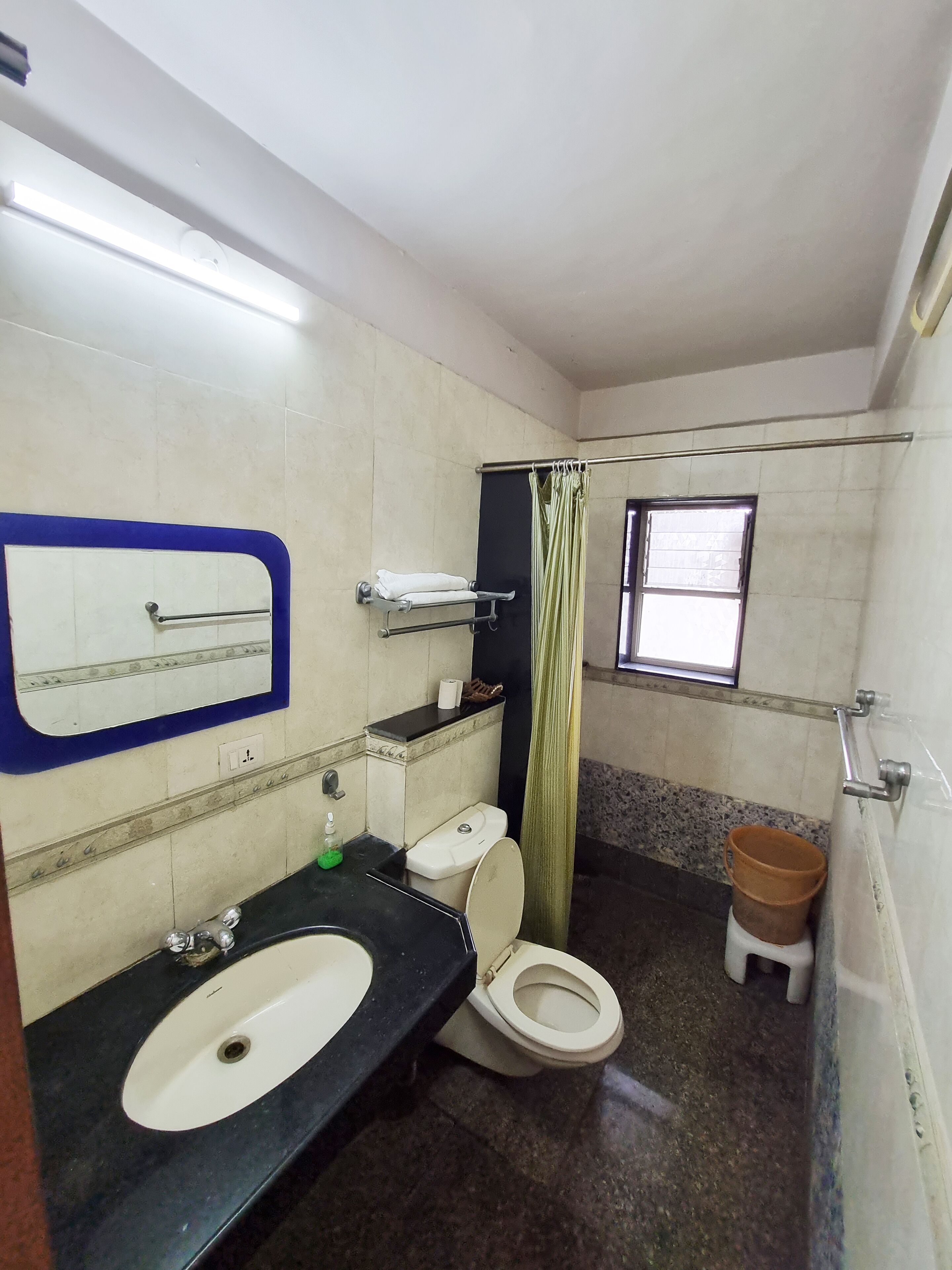 Een kleine badkamer met een wit wastafel, toilet, spiegel en raam.
