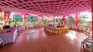 Un espace événementiel intérieur doté d’un haut plafond, de tables et de chaises disposées de manière ordonnée.