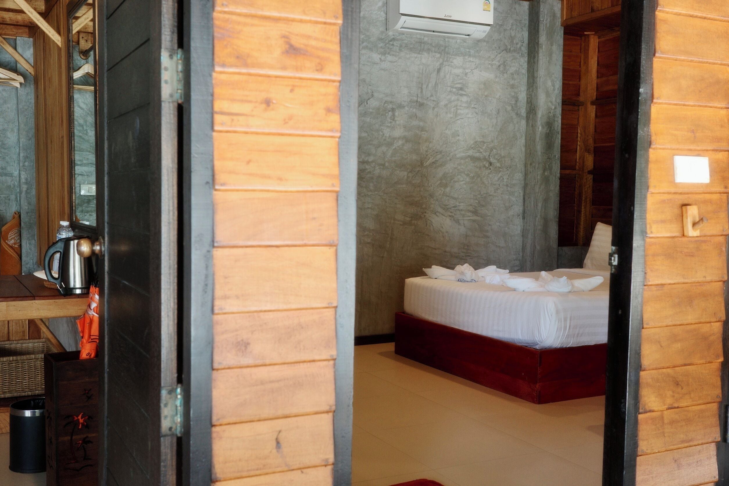 A wooden room with a bed, a coffee maker, and a wall-mounted air conditioner.