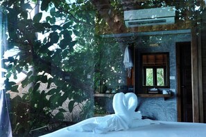 Una habitación con cama, ventana y un estante con objetos.