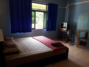 A room with a bed, a television, and a fan. - JP Hometel (Krabi)