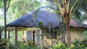 A thatched-roof structure with a covered porch, surrounded by lush tropical vegetation. - Royal Cliff Resort (San Juan)