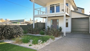 A two-story house with a balcony, a garage, and a landscaped garden. - Sunset at Snapper Point (Aldinga Beach)