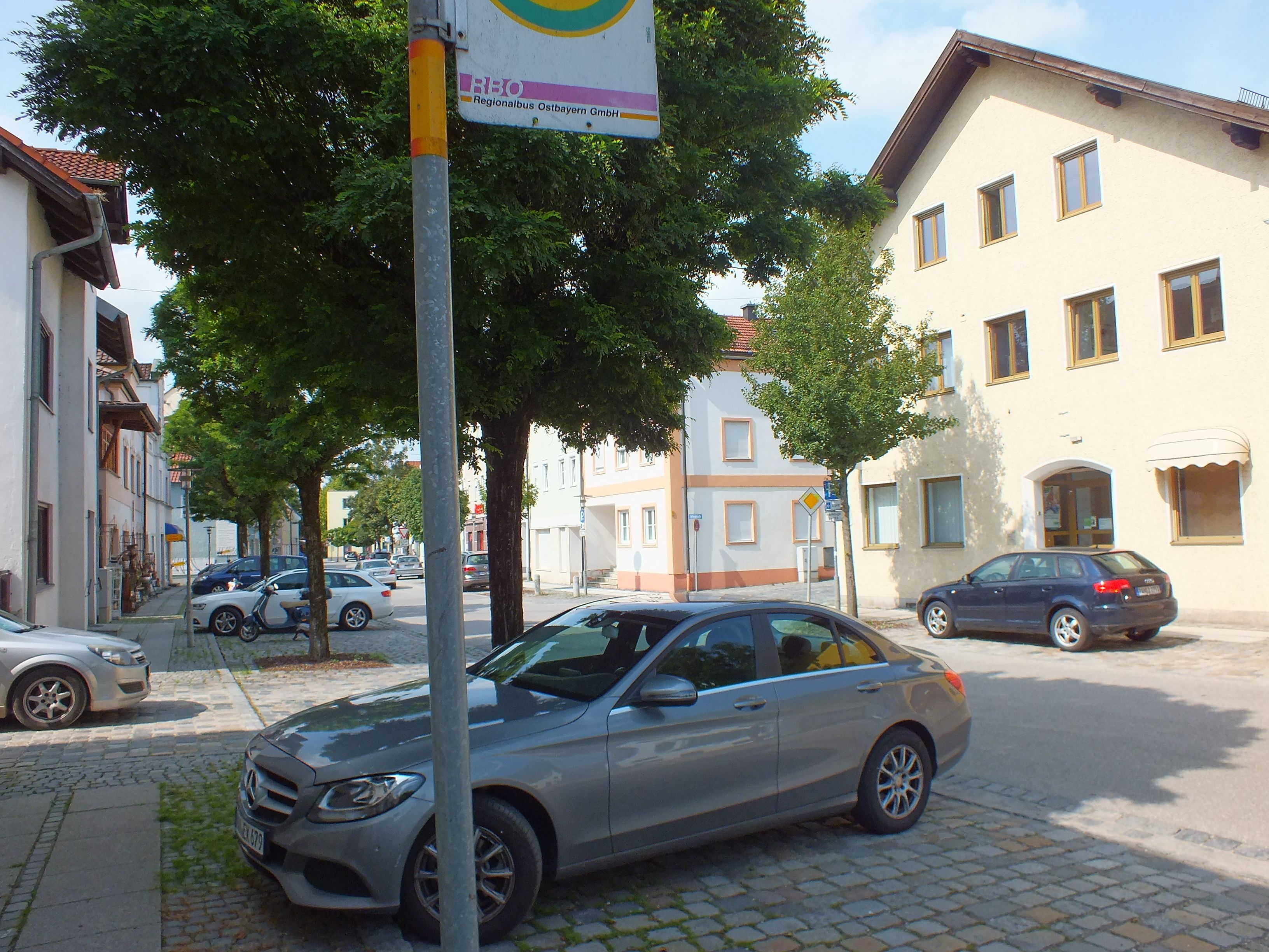 A street with parked cars, buildings, and trees.