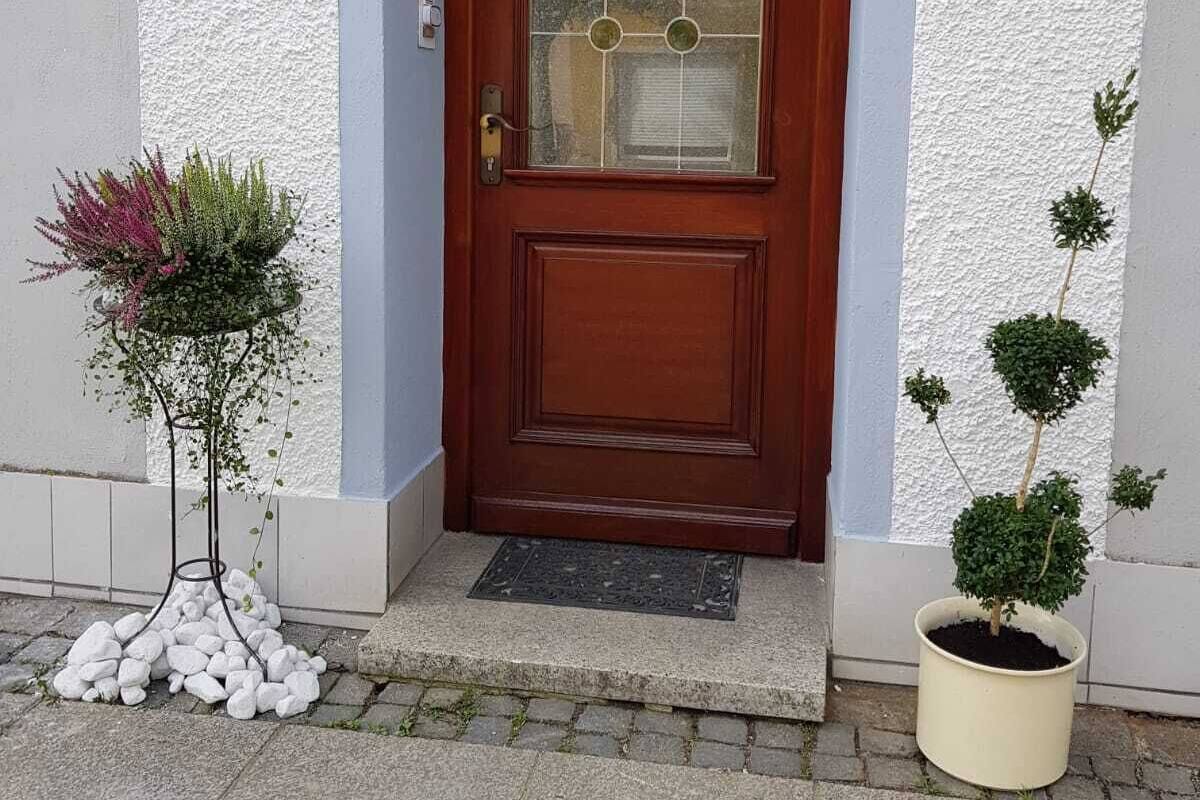 Eine Holztür mit Glasfenster, rechts daneben ein kleiner Blumentopf und ein Schild mit der Nummer 22.